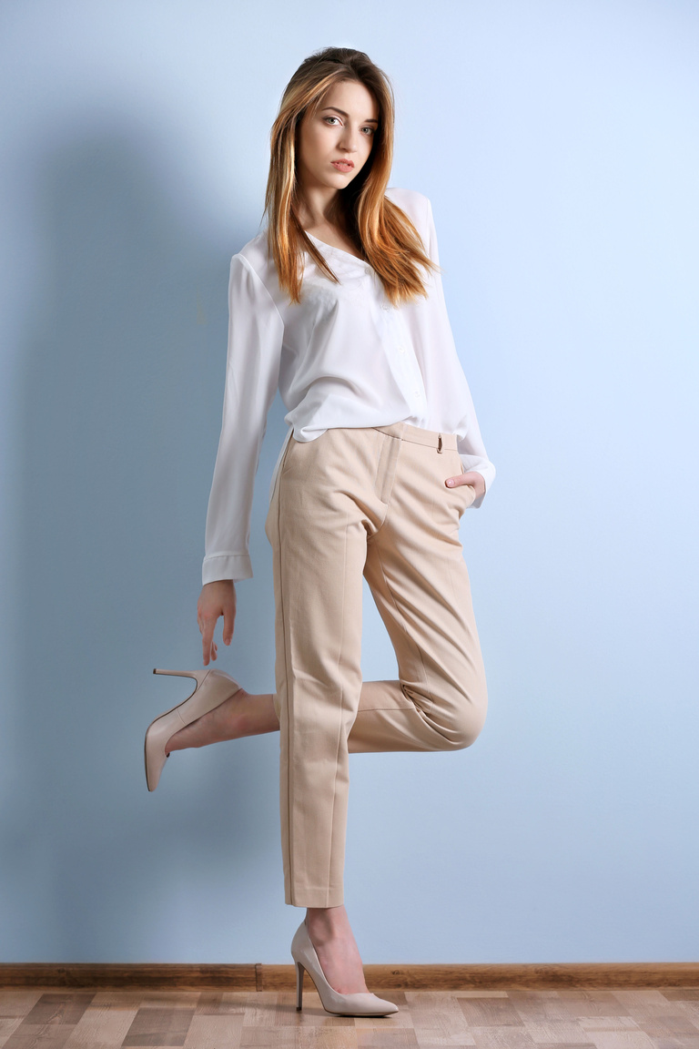 Beautiful Young Woman in a White Shirt and Beige Pants