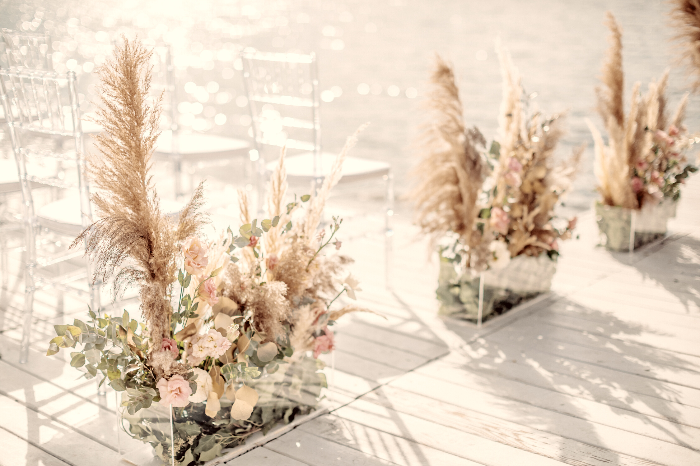 Wedding by the river. Beach wedding venue. Wooden stage with floral decorations